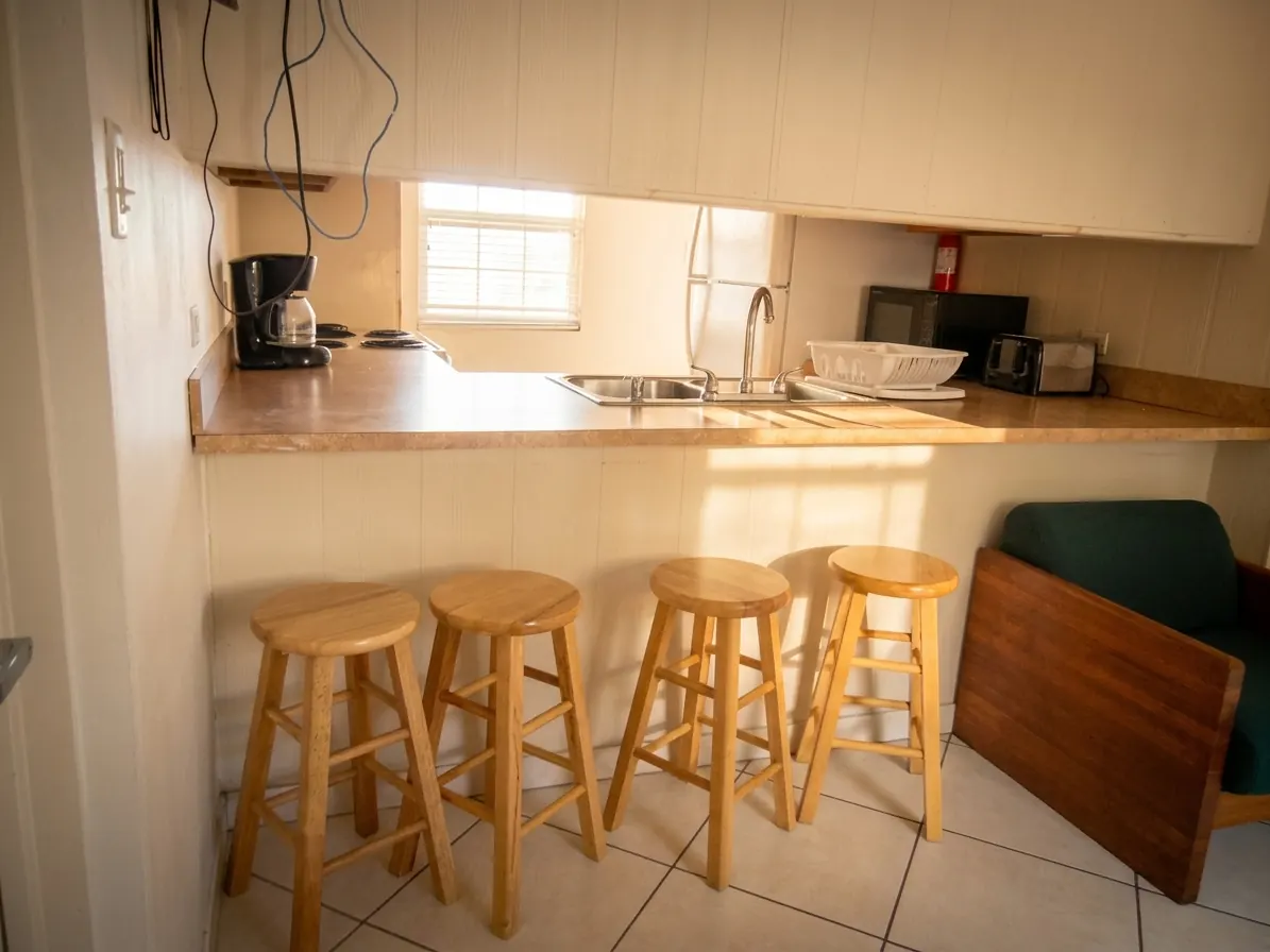 A kitchen counter with bar stools, a sink, a coffee maker and a toaster