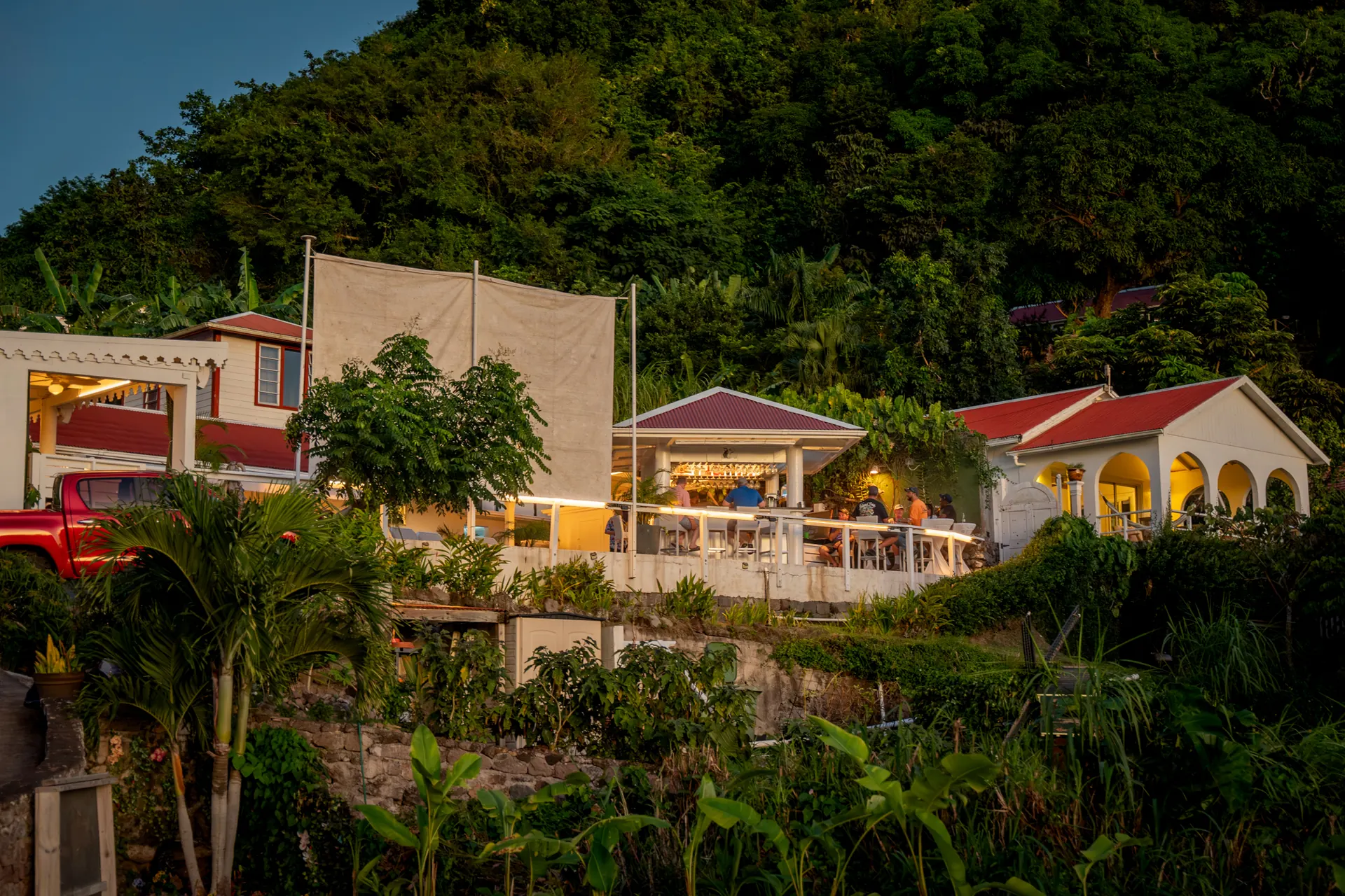 White cottages with red roofs on a steep green hillside above the sea
